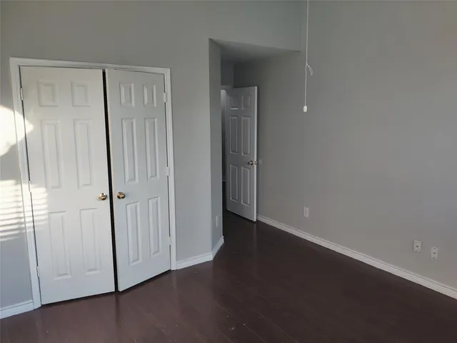 an empty room with wooden floor closet and windows