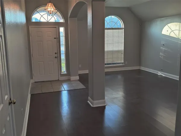 an empty room with wooden floor cabinet and windows