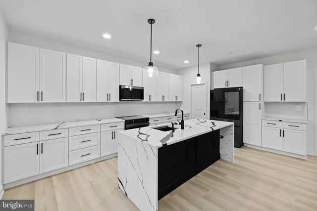 a large white kitchen with kitchen island a sink a stove and a refrigerator