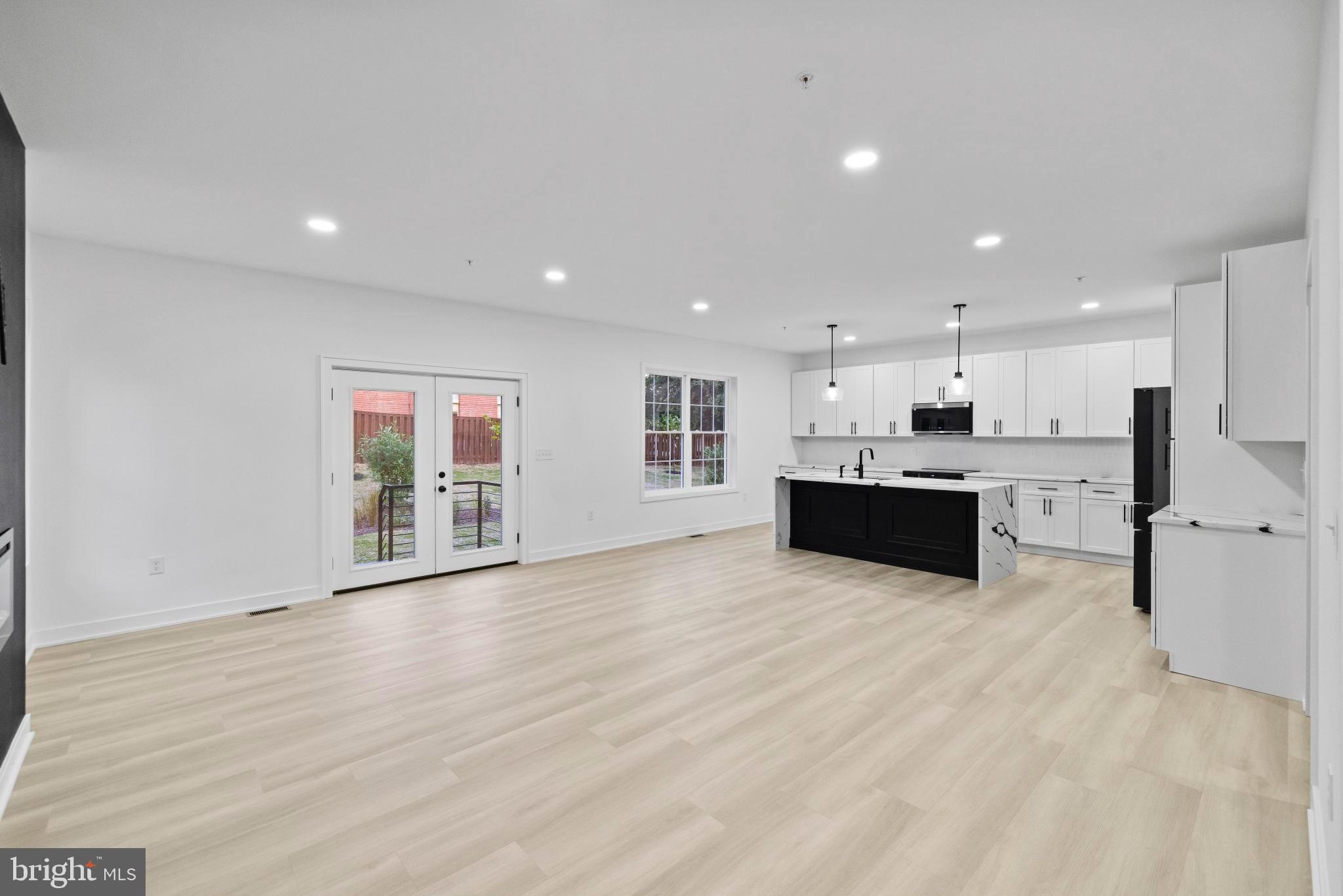 235 Brock Bridge Road Laurel, MD 20724 - Photo 4 of 59 a large white kitchen with kitchen island a sink wooden floor and a refrigerator