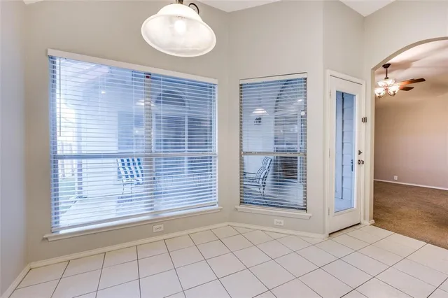 a view of an empty room with a fireplace and chandelier fan