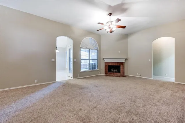 a view of an empty room with a fireplace and a chandelier fan