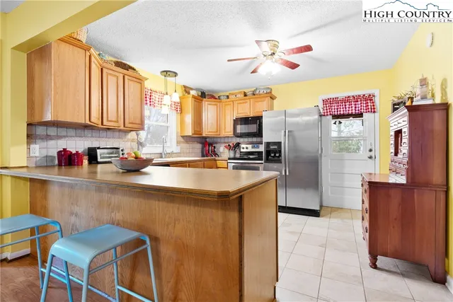 a kitchen with stainless steel appliances granite countertop a refrigerator a stove a sink a dining table and chairs with wooden floor