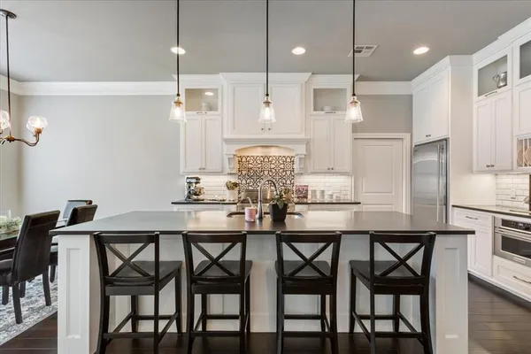 a kitchen with stainless steel appliances granite countertop a dining table chairs and white cabinets