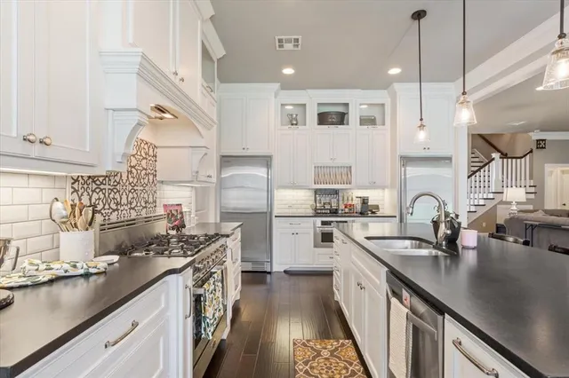 a kitchen with stainless steel appliances granite countertop a sink a stove and a refrigerator