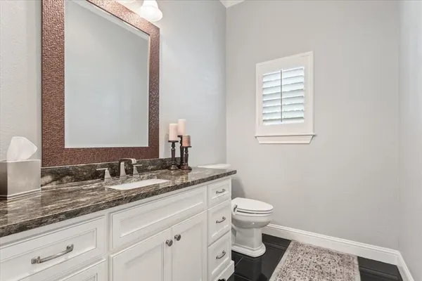 a bathroom with a granite countertop sink a toilet and a mirror