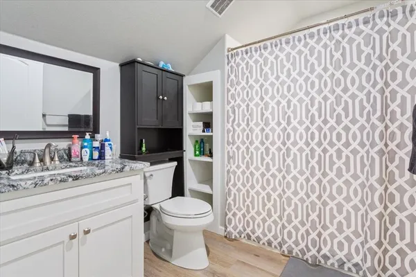 a bathroom with a granite countertop sink toilet mirror and shower