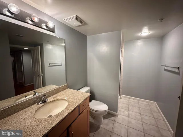 a bathroom with a granite countertop sink a mirror and a toilet