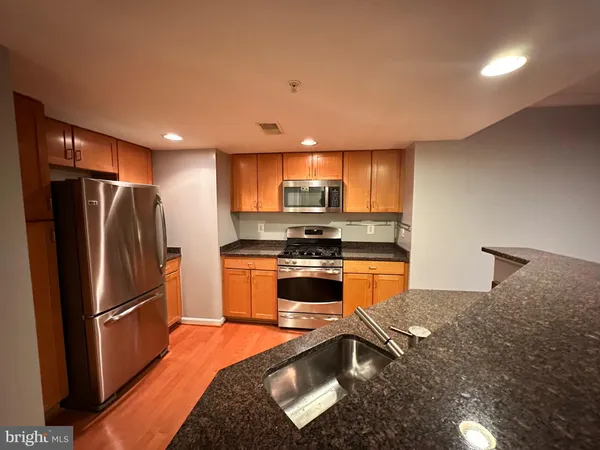 a kitchen with stainless steel appliances granite countertop a refrigerator a stove top oven a sink and dishwasher