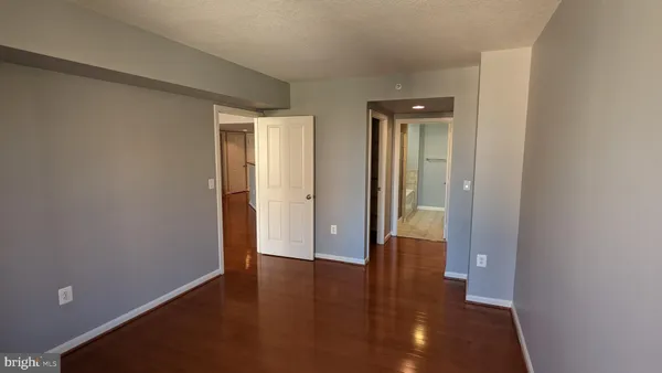 a view of an empty room with wooden floor and closet