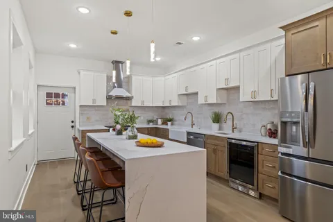 a kitchen with a sink a stove a refrigerator and white cabinets with wooden floor
