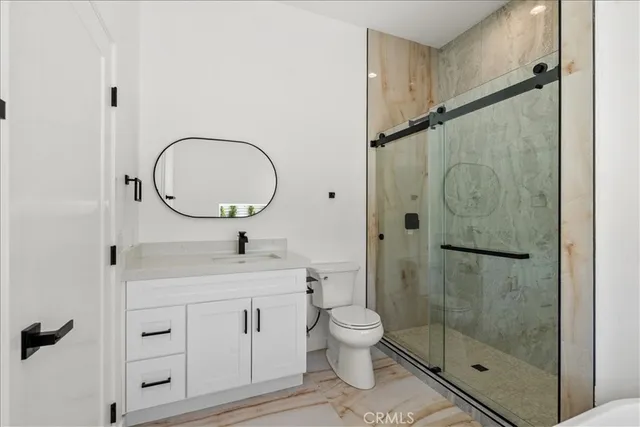 a bathroom with a toilet sink vanity granite and shower