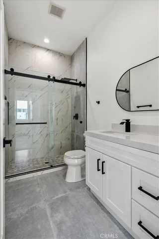 a bathroom with a granite countertop sink a toilet and shower