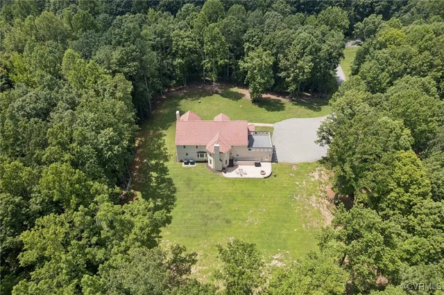 an aerial view of residential house with outdoor space and trees all around