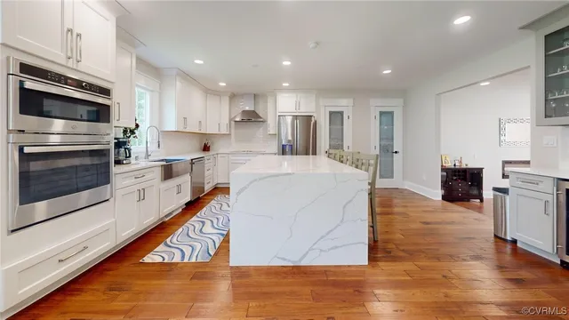 a large kitchen with stainless steel appliances a stove a sink and a microwave