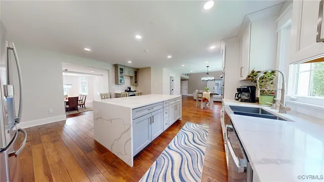 a large white kitchen with sink a counter top space and windows