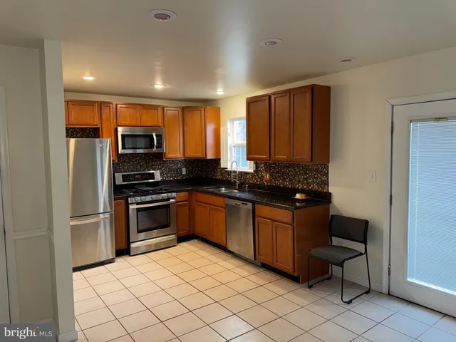 a kitchen with stainless steel appliances granite countertop a refrigerator and a stove top oven