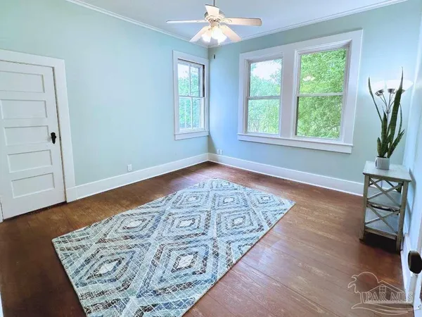 a view of an empty room with window and wooden floor