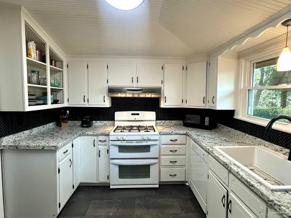 a kitchen with granite countertop a sink stove and cabinets
