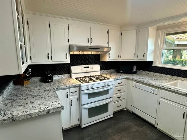 a kitchen with granite countertop a stove a sink and a granite counter tops