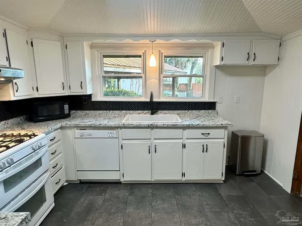 a kitchen with granite countertop white cabinets and window