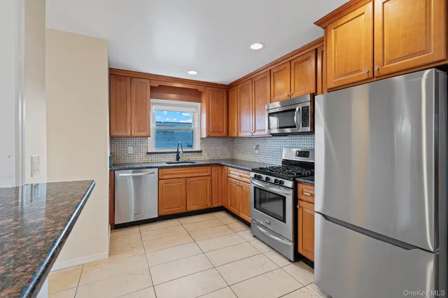 a kitchen with stainless steel appliances granite countertop a refrigerator stove top oven and sink