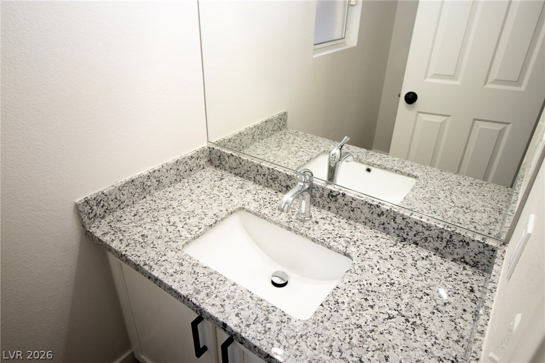 1468 Reef Ridge Court Las Vegas, NV 89128 - Photo 12 of 22 A chic vanity features a modern sink and a spacious granite countertop.