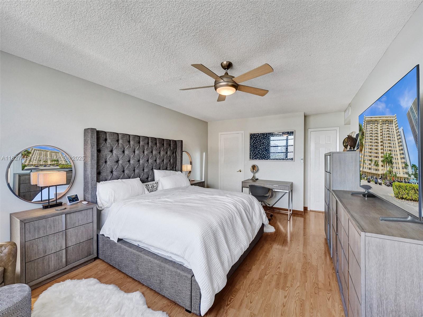 1833 South Ocean Drive, Unit 1702 Hallandale Beach, FL 33009 - Photo 32 of 80 a bedroom with a bed a mirror on dresser and a chandelier