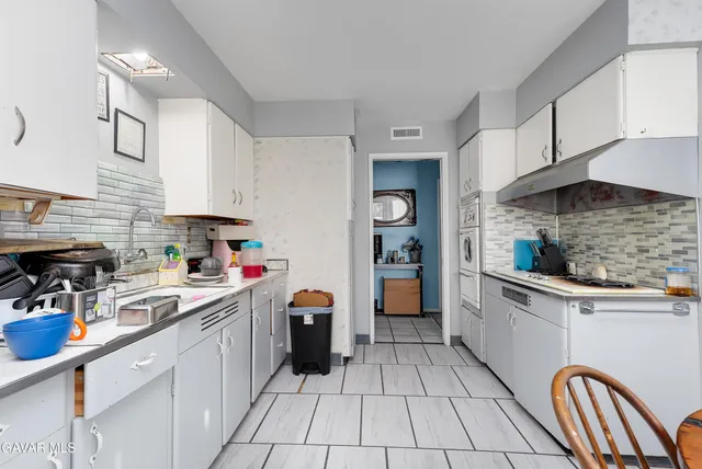 a kitchen with stainless steel appliances a sink a stove top oven a counter space and cabinets