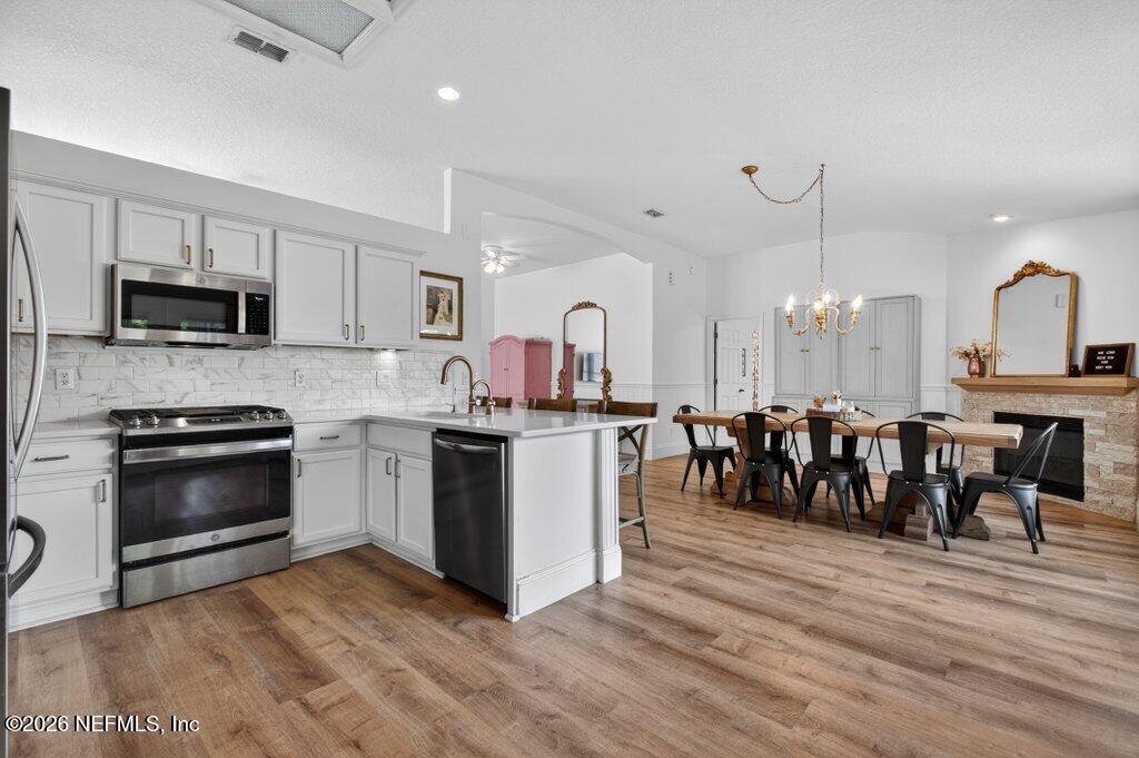 1441 Tintern Lane St. Augustine, FL 32092 - Photo 28 of 57 a kitchen with kitchen island granite countertop a stove top oven a sink a dining table and chairs with wooden floor