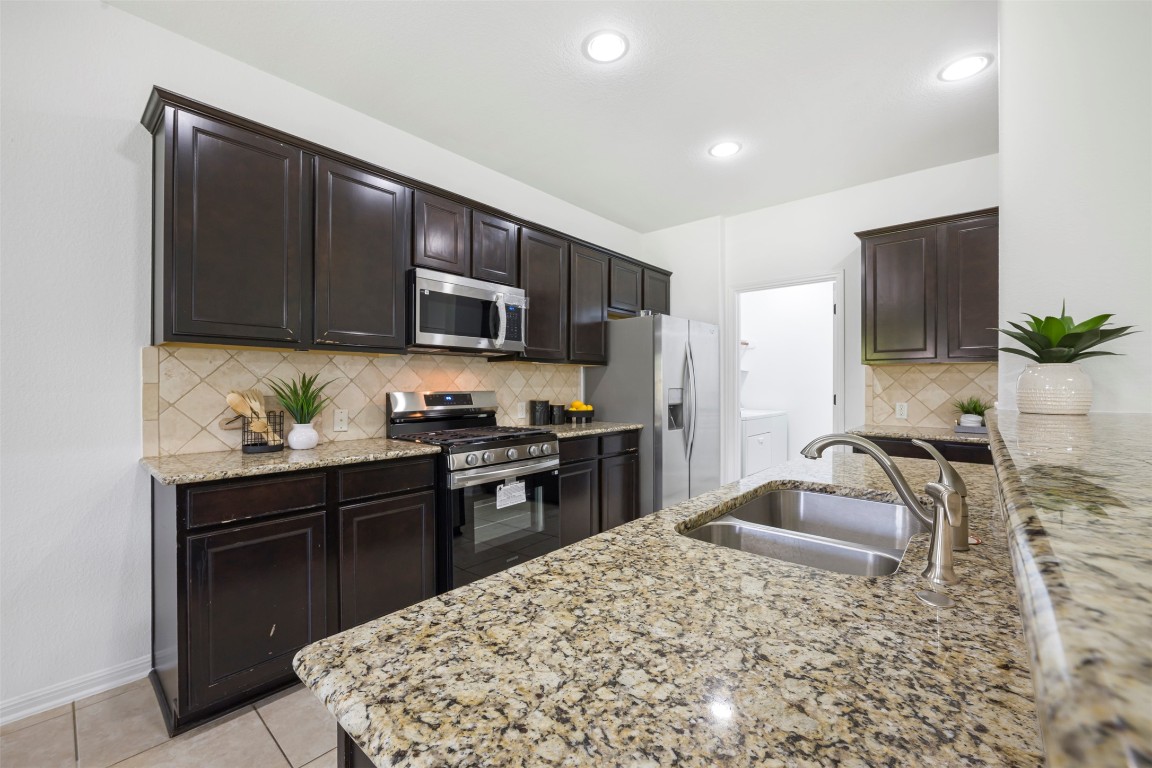 1812 Hidden Springs Path Round Rock, TX 78665 - Photo 11 of 39 a kitchen with kitchen island granite countertop a sink stove and refrigerator