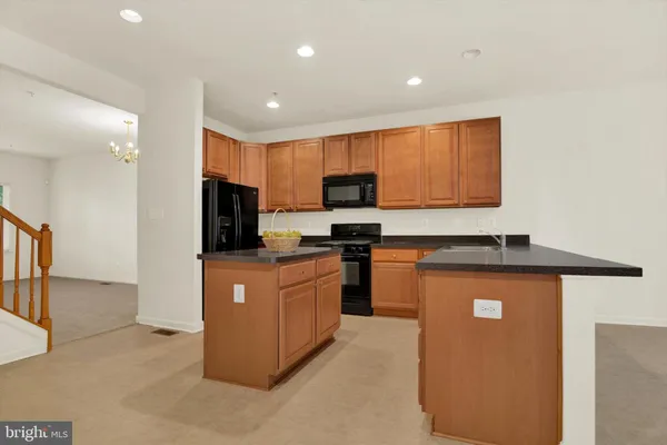 a kitchen with stainless steel appliances granite countertop a stove top oven a sink a refrigerator and white cabinets with wooden floor