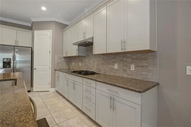 a kitchen with granite countertop white cabinets and stainless steel appliances