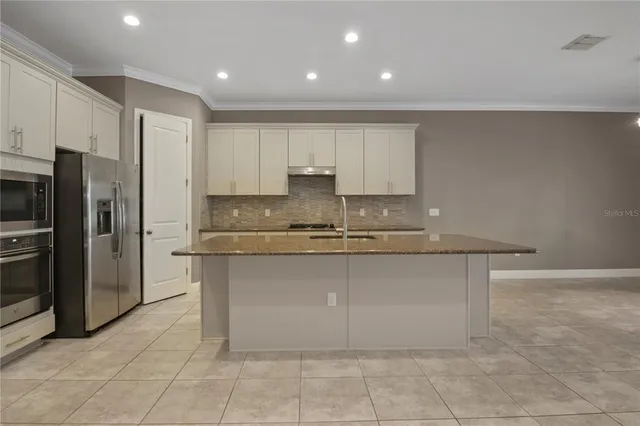 a large kitchen with stainless steel appliances granite countertop a stove a sink and a refrigerator