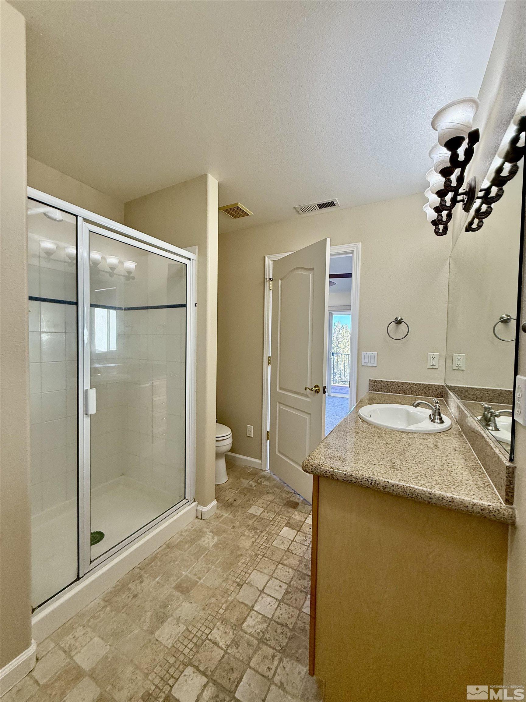 1090 Spring Drive Carson City, NV 89703 - Photo 27 of 31 a bathroom with a granite countertop sink a mirror and a shower