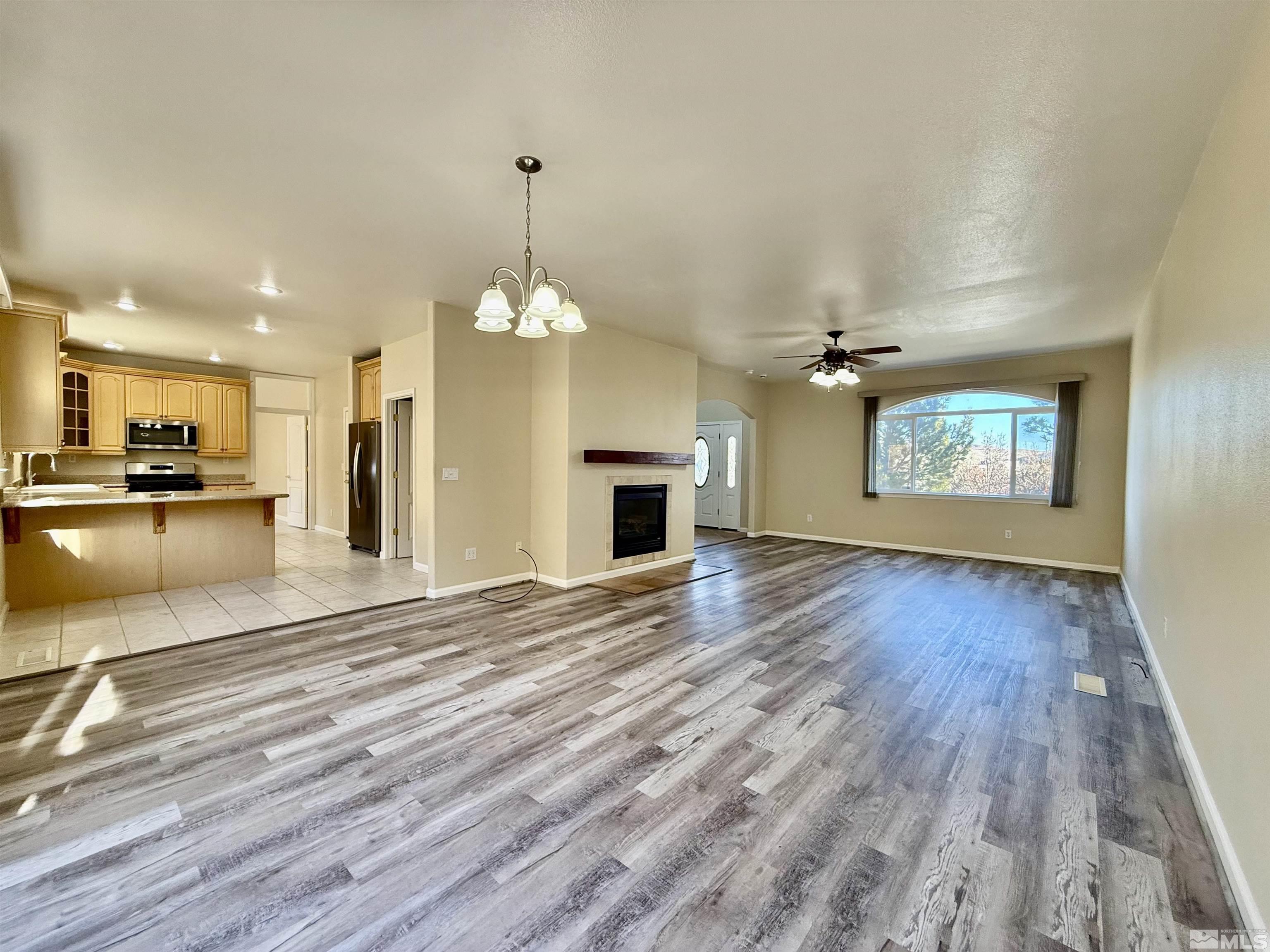 1090 Spring Drive Carson City, NV 89703 - Photo 5 of 31 an empty room with wooden floor fireplace and kitchen view