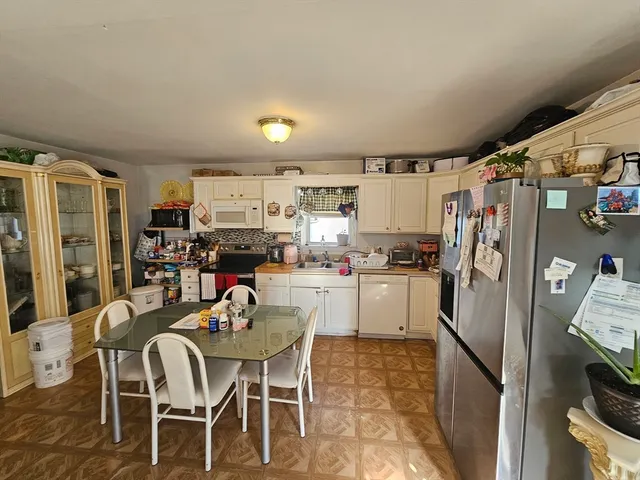 a kitchen with a refrigerator and table chairs