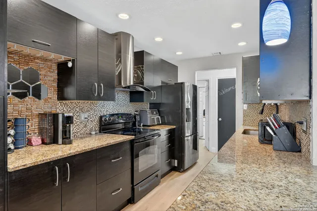 a kitchen with stainless steel appliances granite countertop a sink a stove and a refrigerator
