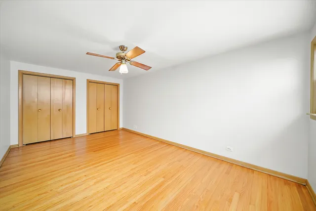 a view of an empty room and window with a ceiling fan