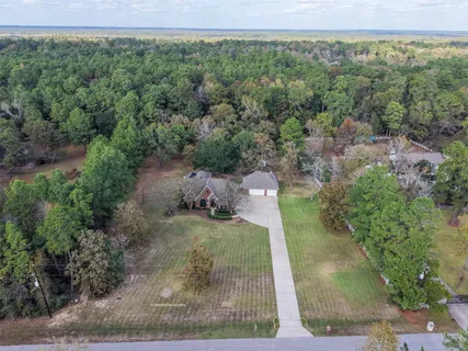 an aerial view of a houses with outdoor space and trees all around