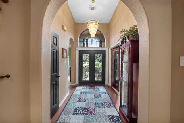 a view of a hallway with wooden floor and a chandelier