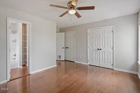 an empty room with wooden floor ceiling fan and windows
