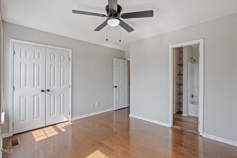 an empty room with wooden floor fan and windows