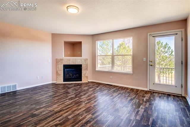 3579 Indigo Ridge Point Colorado Springs, CO 80910 - Photo 12 of 33 Living room with LVP flooring, a gas fireplace and a walk out to deck