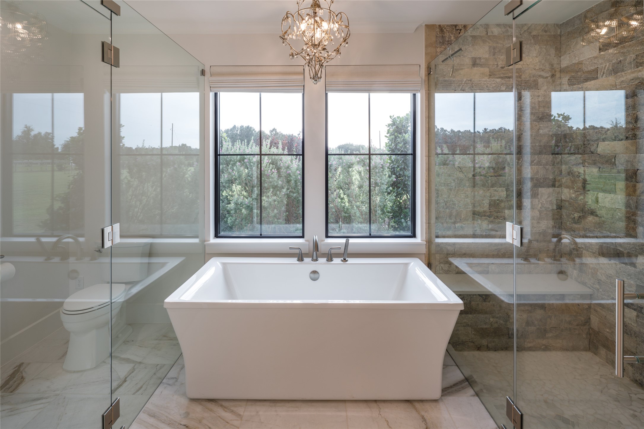 24118 Margerstadt Road Hockley, TX 77447 - Photo 22 of 46 Expansive windows frame the freestanding soaking tub while bringing wide pasture views into the primary bathroom throughout the day. Clean finishes, generous proportions, and soft natural light give the space a calm and refined atmosphere.
