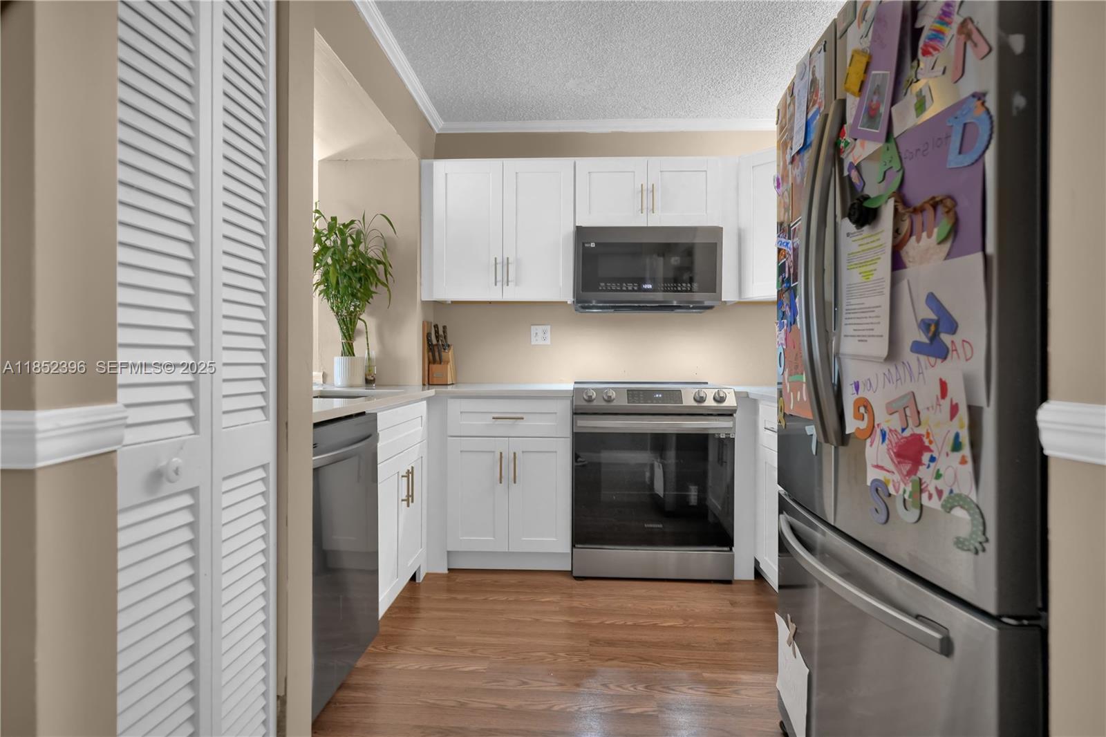10194 Southwest 77th Court Miami, FL 33156 - Photo 6 of 25 a kitchen with stainless steel appliances a stove a microwave and cabinets