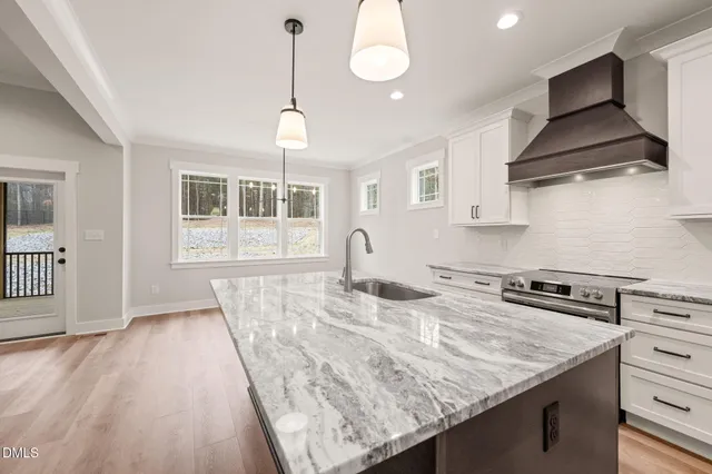 a kitchen with stainless steel appliances granite countertop a sink a stove and a wooden floors