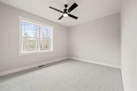 an empty room with a window and a fan