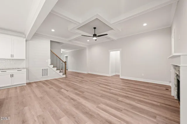 a view of an empty room with a window and a kitchen