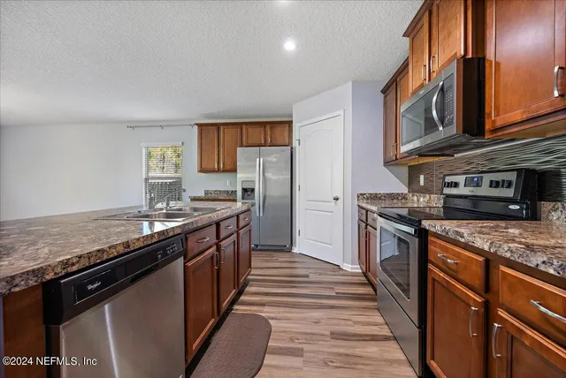 a kitchen with stainless steel appliances granite countertop a stove a sink and a refrigerator